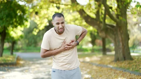 A young man suffered a heart attack or chest pain during a morning run in a park Stock Footage 234880902