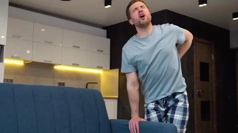 Young man suffering from backpain while lifting sofa at home Stock Footage 242205557