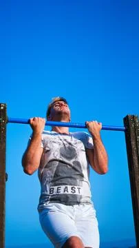 Young man suffering doing pullups Stock Photos