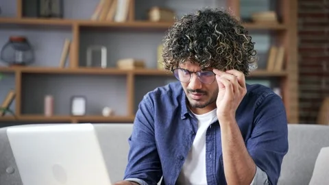 Young man suffering from eye fatigue and headache while working on a laptop  Stock Footage 334229299