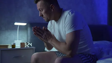 Young man suffering from insomnia while sitting in bed  at night. Depressed.. Stock Footage 289561691