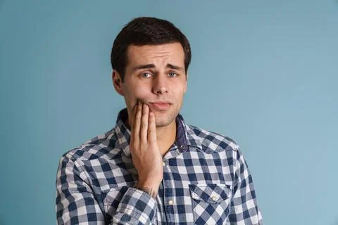 Young man suffering from a tooth ache over blue Stock Photos