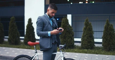 Young man in suit checking phone before riding his bicycle in the morning Stock Footage 92616989