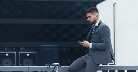 Young man in suit checking phone before riding his bicycle in the morning Stock Footage 92635172