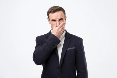 Young man in suit closing nose due to bad smell Stock Photos