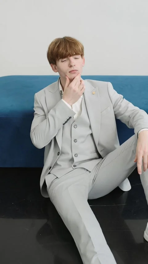 Young man in suit sitting on blue couch Stock Footage 274163025