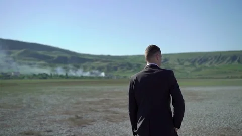 Young man in suit staying in a field Stock Footage