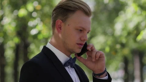 Young man in a suit talking on the phone in the park Vidéo 81500806