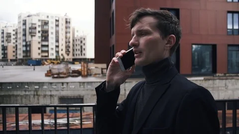 Young man in suit using smartphone. Building under construction at background Stock Footage 79417033