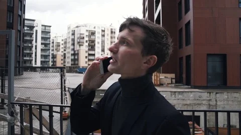 Young man in suit using smartphone. House under construction at background Stock Footage 79417496
