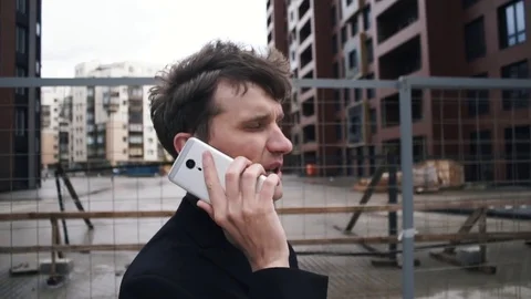 Young man in suit using smartphone. House under construction at background Stock Footage 79417649