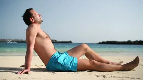 Young man sunbathing on tropical beach HD Stock Footage 10875734