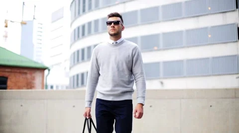 Young man with sunglasses and bag walking in city Stock Footage
