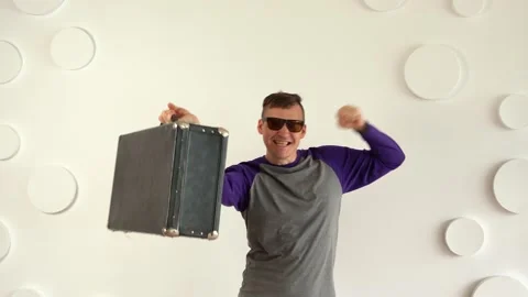 Young man in sunglasses with large suitcase against white patterned wall. Stock Footage 130803995