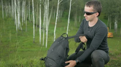 Young man in sunglasses pulls the phone out of the bag and talking. Against the Stock Footage 66577998