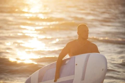 Young man at sunset with SUP Stock Photos