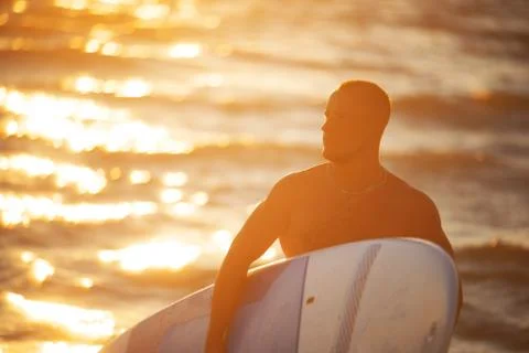 Young man at sunset with SUP Stock Photos
