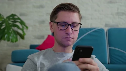 Young man surf the internet using a mobile phone, staying isolated at home. Stock Footage 144108465