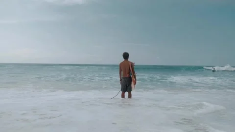 Young man with surfboard stading on the beach Stock Footage 245023582