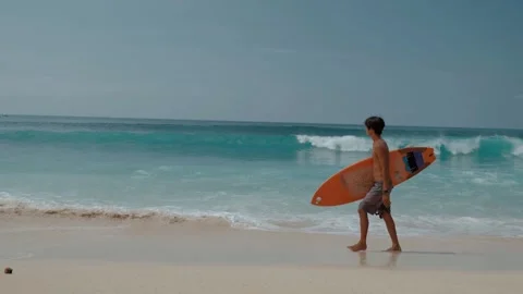 Young man with surfboard walking on the beach Stock Footage 245022150