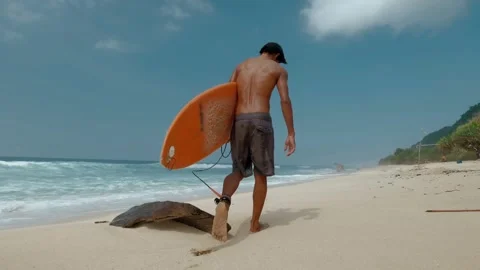 Young man with surfboard walking on the beach Stock Footage 245022186