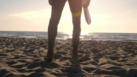 Young man surfer in wetsuit picks up surf board lying down on the sand at the Stock Footage 85457623