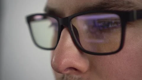 Young man surfs the internet. Reflection of a pc monitor in glasses. The IT Stock Footage 230289263