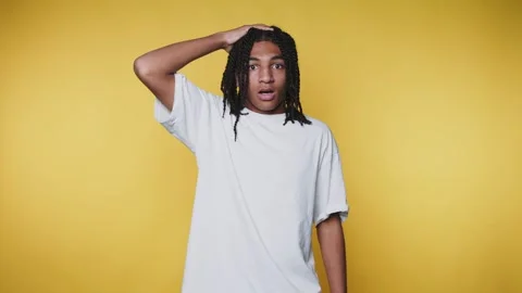 Young man with a surprised expression holds his hand on his head, conveying.. Stock Footage 313280309