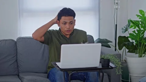 Young man surprised by sudden ceiling leak while using his laptop at home Stock Footage 331158727