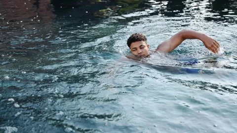 Young man swimming laps in refreshing outdoor pool water during summer vacation Stock Footage 328160190