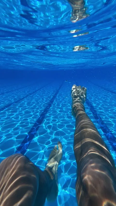 A young man swims in a blue pool and dives underwater Stock Footage 237761334