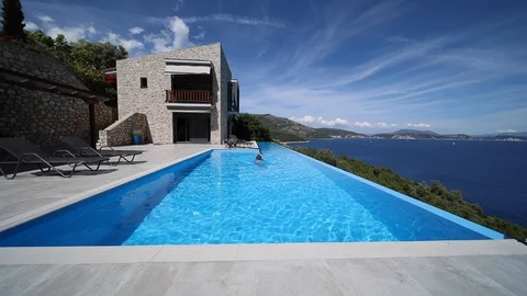 Young man swims in the infinity pool 스톡 동영상 116900578
