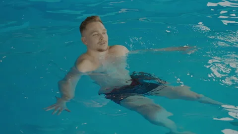 A young man swims in a pool at a spa center. Stock Footage 306660599