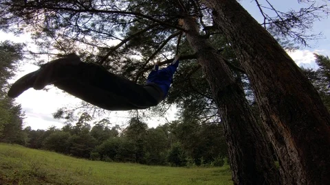 A young man is swinging on a tree. A young man is hanging on a tree. Stock Footage 93892659