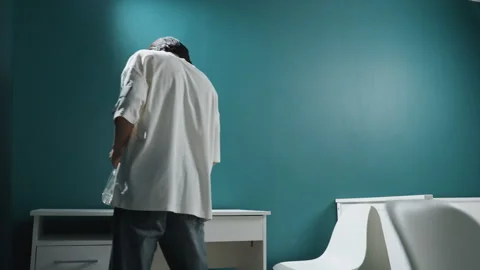 Young man systematically disinfects white desk near teal wall. Male handyman Stock Footage 346233776