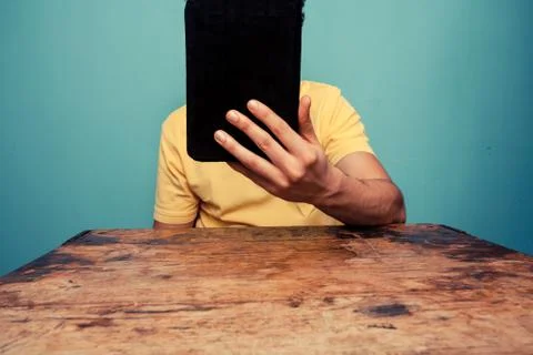 Young man at table reading on tablet Foto stock