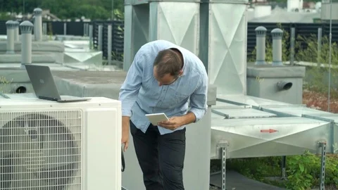 Young man with tablet checking air conditioning on roof Stock Footage 79951223