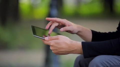 The Young Man With the Tablet Computer on a Bench in the Park Video stock 50995012