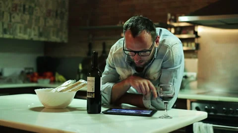 Young man with tablet computer drinking wine in the kitchen Stock Footage 36640394