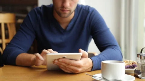 Young man with tablet computer drinking tea in cafe Stock Footage 67863149
