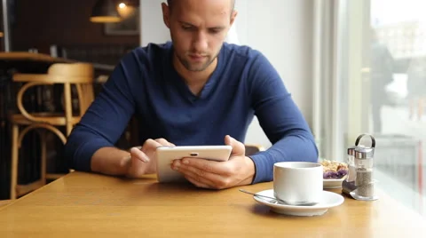 Young man with tablet computer drinking tea in cafe Stock Footage 67863169