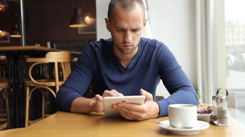 Young man with tablet computer drinking tea in cafe Stock Footage 67863190