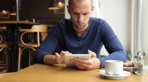 Young man with tablet computer drinking tea in cafe Stock Footage 67863208