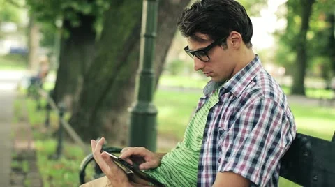 Young man with tablet computer in park, steadicam shot HD Stock Footage 11824726