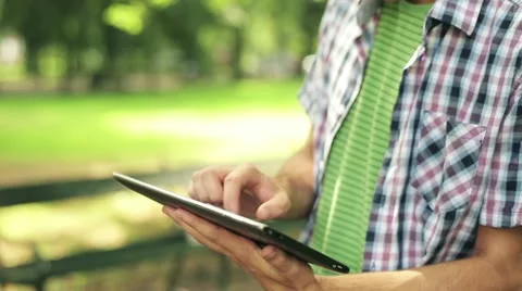 Young man with tablet computer in park, steadicam shot HD Video stock 11824762