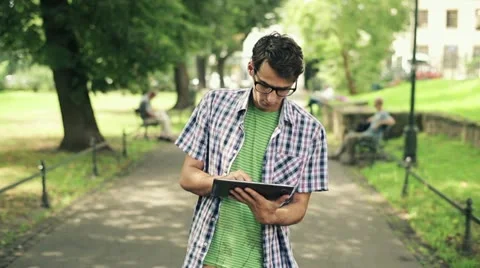 Young man with tablet computer in park, steadicam shot HD Stock Footage 11824819
