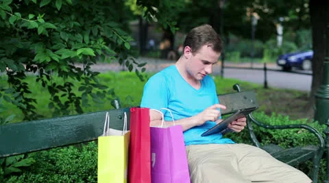 Young man with tablet computer sitting in the park HD Stock Footage 24958156