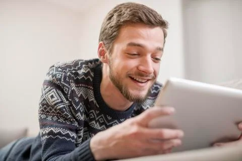 Young man with tablet computer in their hands, on the couch at home. Stock Photos