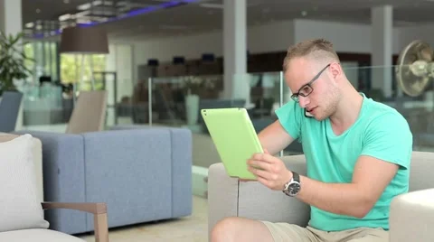 Young man with tablet pc and smartphone in hotel lobby. Stock Footage 53606784
