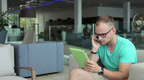 Young man with tablet pc and smartphone in hotel lobby. Stock-Footage 54945488